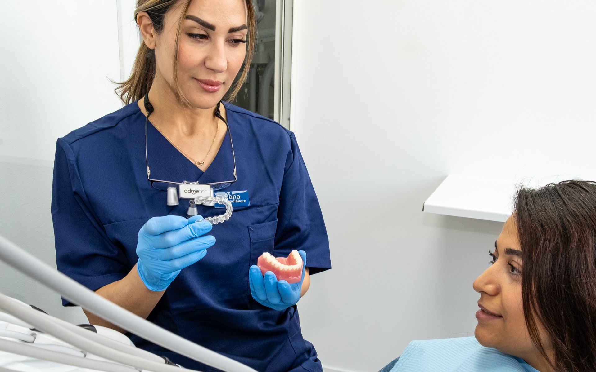 En leende kvinnlig tandläkare står vänligt mot kameran på Svea Dentals klinik i Göteborg, redo för käkkirurgi och professionell tandvård.