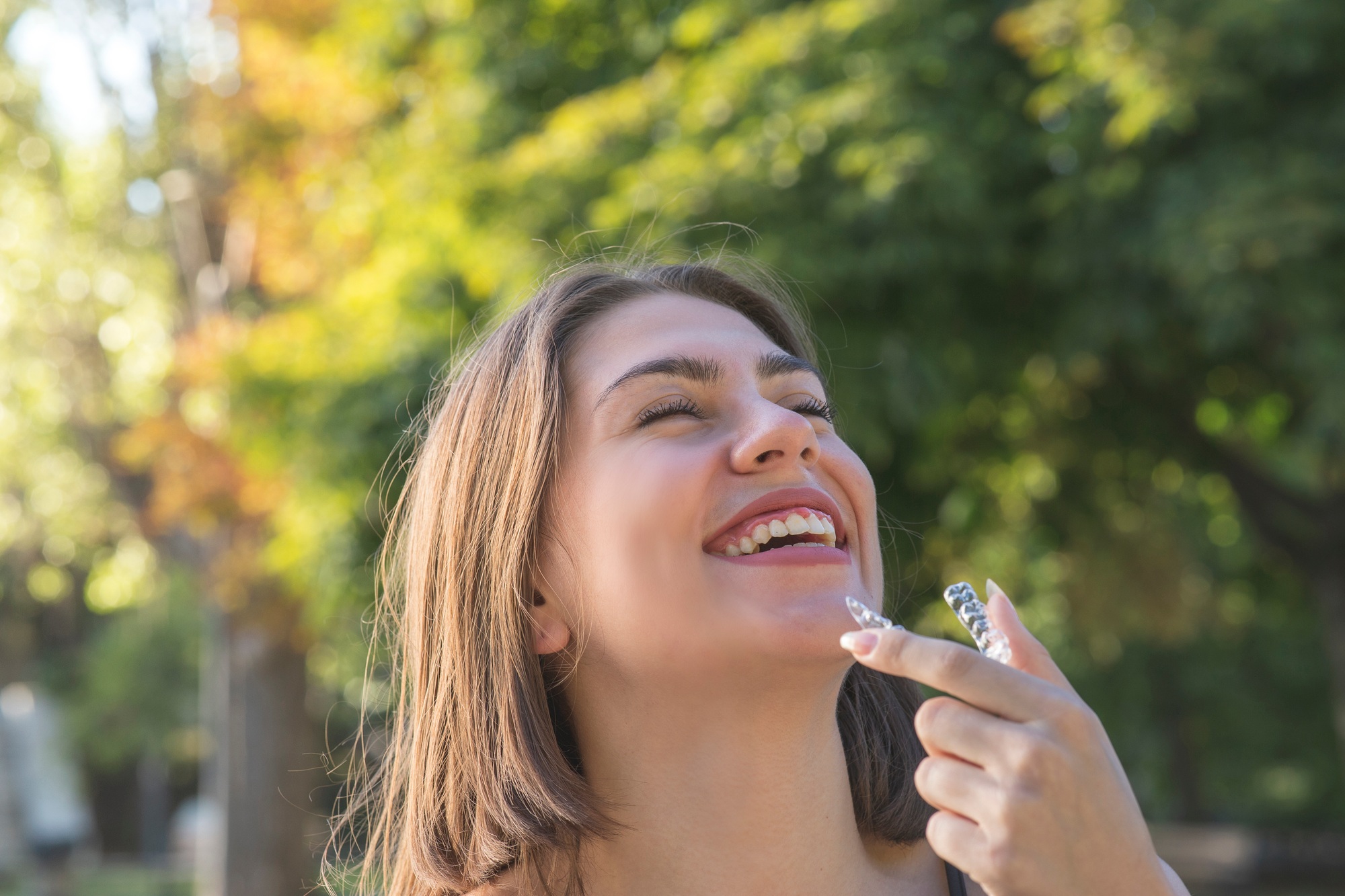 Beautiful smiling Turkish woman is holding an invisalign bracer